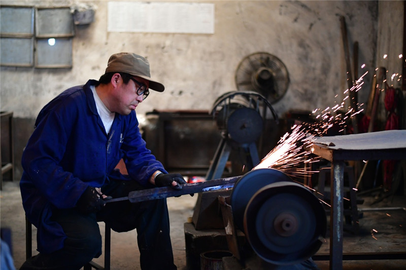 4月12日,在河南省西平县,铸剑师傅在用机器粗磨剑条。