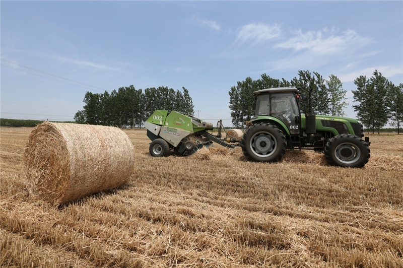 6月4日,一台秸秆打捆机在山东省临沂市郯城县东秦村田间进行打捆作业。