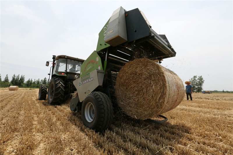 6月4日,一台秸秆打捆机在山东省临沂市郯城县东秦村田间进行打捆作业。